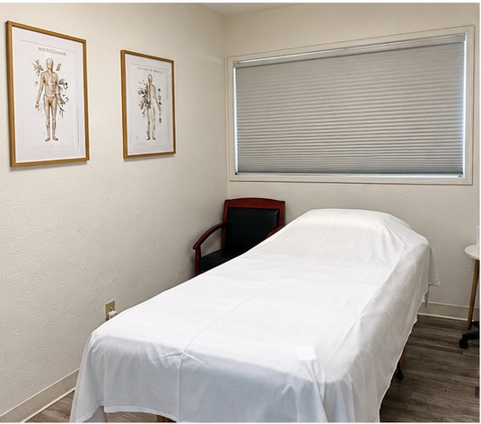 Treatment table with acupuncture charts on the wall